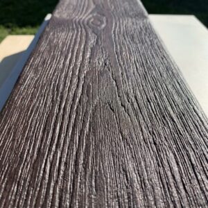 Close-up on the rich texture of a dark faux beam in direct sunlight.